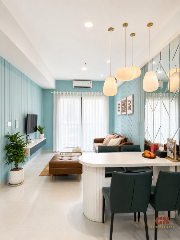 Modern living room at Compass Stay with leather sofa, dining table, teal wall, plants, and soft natural light.