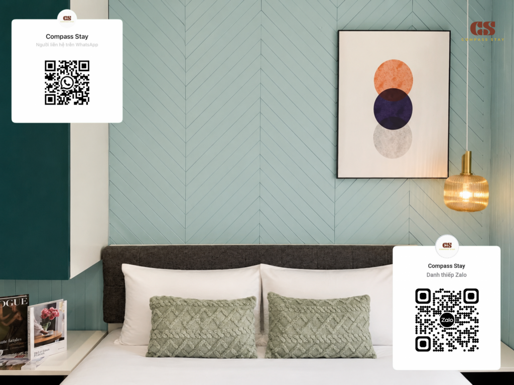 Modern Compass Stay serviced apartment bedroom with teal wall, natural light, and clean white bedding in District 1 Ho Chi Minh City.